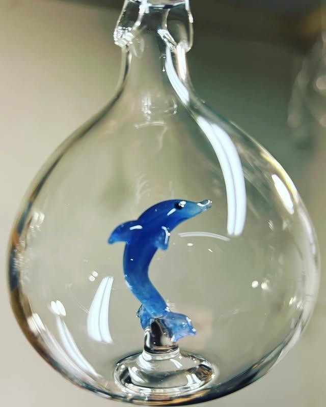 Clear hanging glass orb with a small cobalt-blue dolphin stood inside