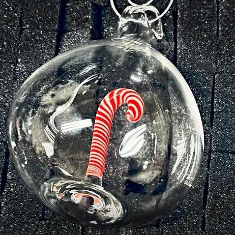 Clear glass ornament with a red-and-white striped candy cane sealed inside