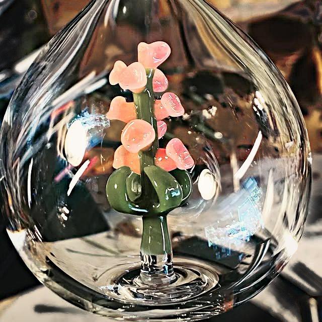 Clear glass ornament enclosing a green stem with pale pink blossoms